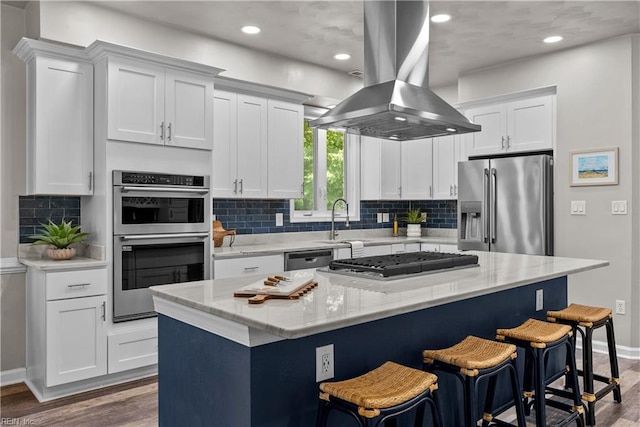 2300 Perez Way, Virginia Beach, VA 23456 - kitchen featuring appliances with stainless steel finishes, island exhaust hood, a sink, white cabinetry, and wood finished floors