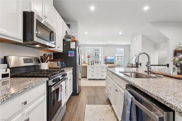 109 Big Woods Dr, Poquoson, VA 23662 - kitchen featuring appliances with stainless steel finishes, a sink, white cabinets, light wood-type flooring, and light stone counters
