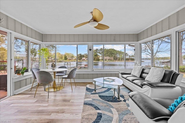 sunroom / solarium featuring a water view, healthy amount of natural light, crown molding, and wood finished floors