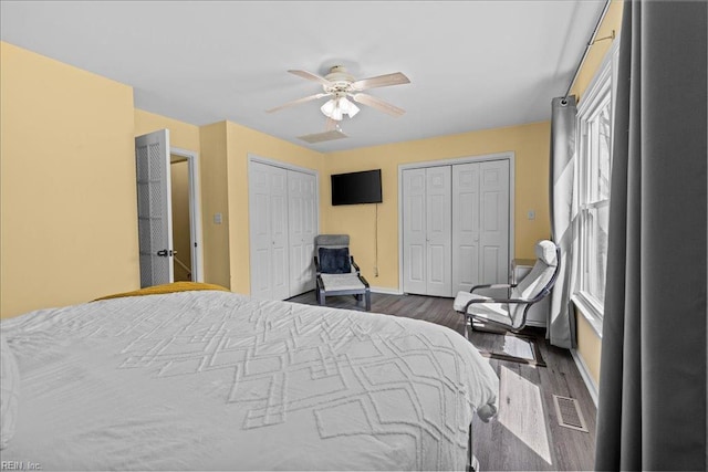 bedroom with multiple closets, wood finished floors, ceiling fan, and baseboards