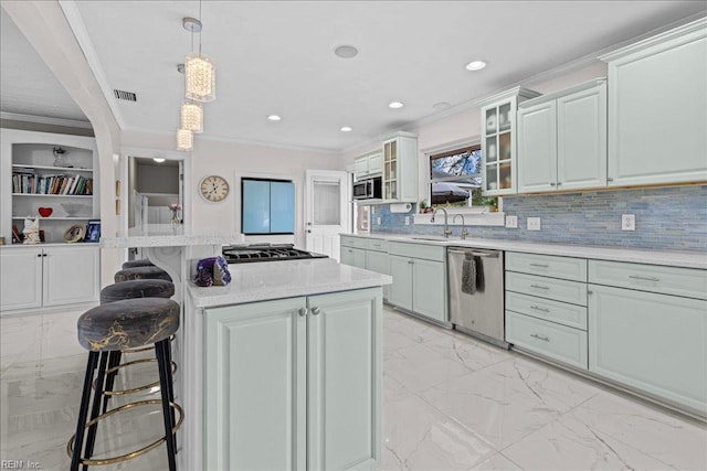 kitchen featuring appliances with stainless steel finishes, crown molding, light marble finish floors, light countertops, and a breakfast bar area
