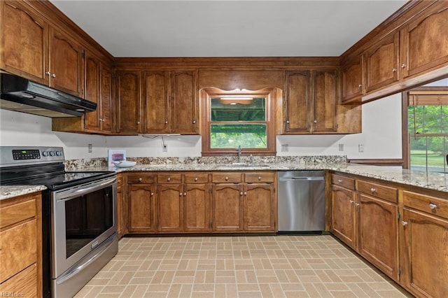 104 Beechwood Dr, Franklin, VA 23851 - kitchen with appliances with stainless steel finishes, under cabinet range hood, brick patterned flooring, a sink, and light stone countertops