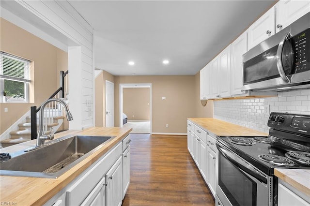 kitchen with appliances with stainless steel finishes, a sink, wooden counters, and recessed lighting