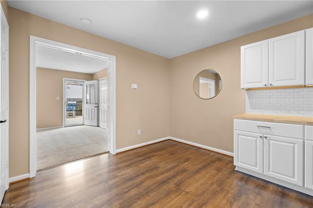 unfurnished dining area with baseboards and dark wood-style floors