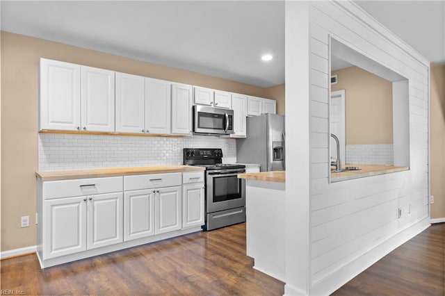 kitchen featuring stainless steel appliances, tasteful backsplash, white cabinets, dark wood-style floors, and a sink