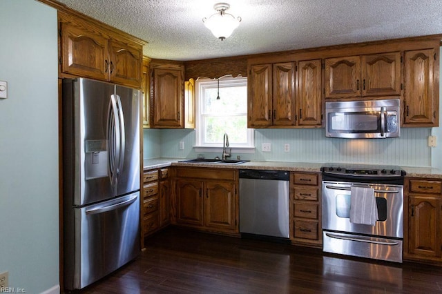 125 Messick Rd, Poquoson, VA 23662 - kitchen featuring appliances with stainless steel finishes, a sink, a textured ceiling, light countertops, and brown cabinets
