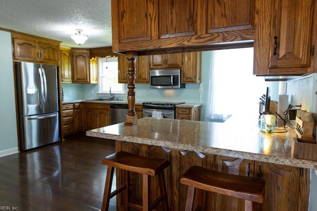 125 Messick Rd, Poquoson, VA 23662 - kitchen with stainless steel appliances, a peninsula, brown cabinets, and a textured ceiling
