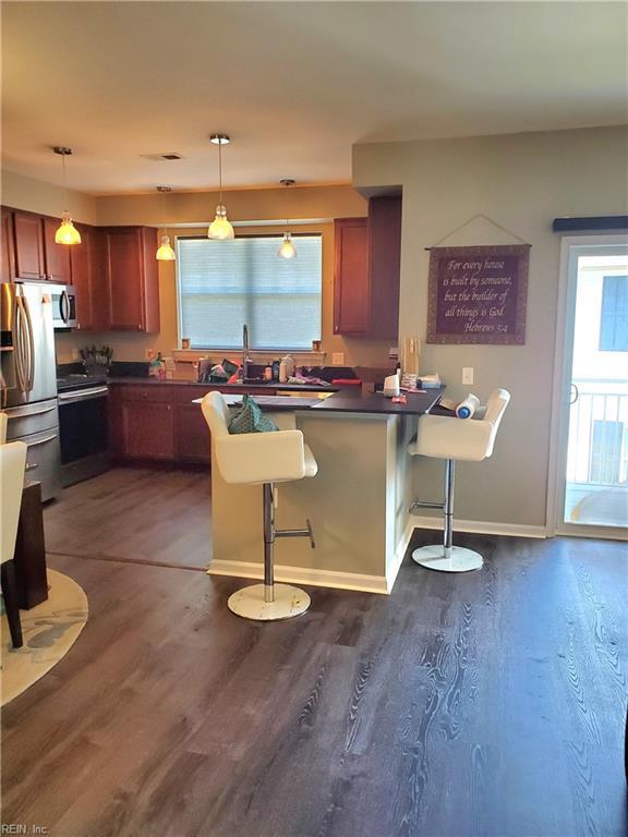 kitchen featuring appliances with stainless steel finishes, dark countertops, dark wood-style floors, a peninsula, and decorative light fixtures
