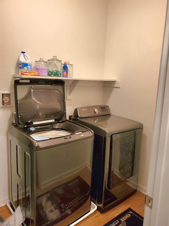 washroom with washing machine and clothes dryer and wood finished floors