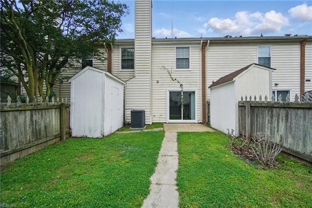 back of property with a shed, central air condition unit, a chimney, and an outdoor structure