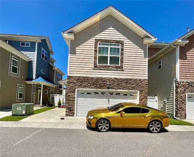 view of front of house with stone siding, a garage, driveway, and fence