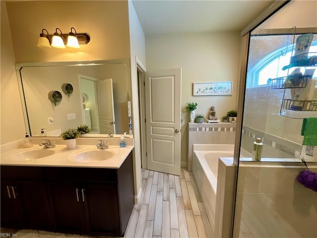 full bath featuring a bath, double vanity, a shower stall, and wood finished floors