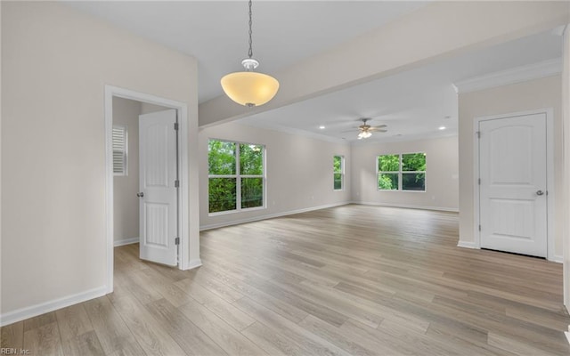 empty room featuring healthy amount of natural light, baseboards, light wood-type flooring, ceiling fan, and ornamental molding