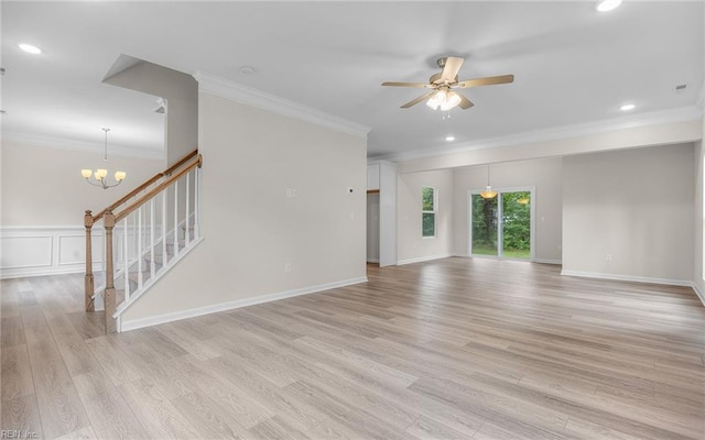 unfurnished living room featuring ceiling fan, light wood finished floors, ornamental molding, stairs, and a chandelier