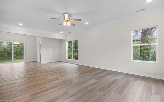 empty room featuring healthy amount of natural light, a ceiling fan, light wood-type flooring, crown molding, and baseboards