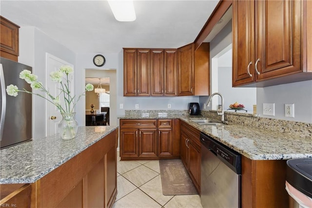 6701 Burbage Landing Cir, Suffolk, VA 23435 - kitchen featuring stainless steel appliances, a sink, brown cabinets, light stone counters, and light tile patterned floors