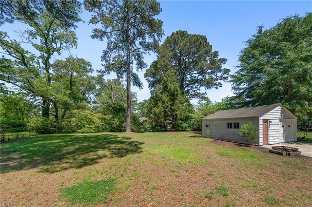 504 Amster Ln, Chesapeake, VA 23323 - view of green lawn featuring an outbuilding, a fire pit, and a detached garage