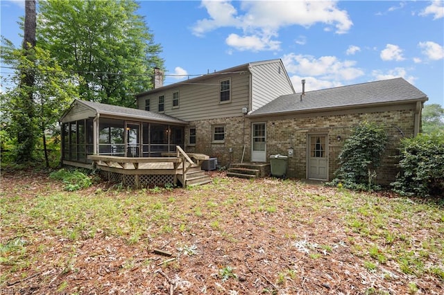 back of property with a sunroom, brick siding, and a wooden deck