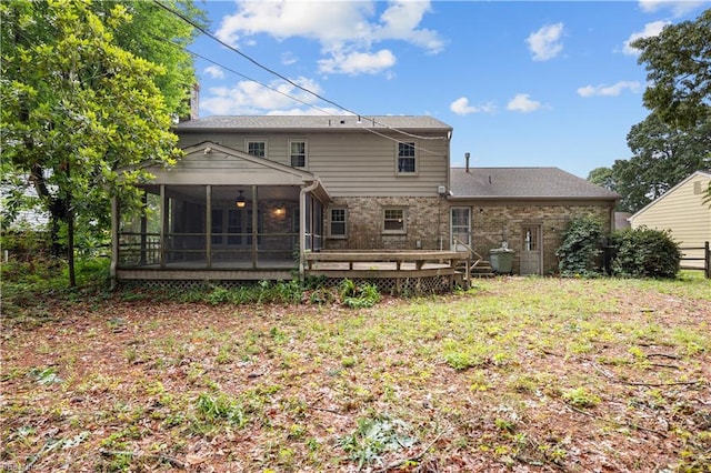 back of property featuring a sunroom, a wooden deck, and brick siding