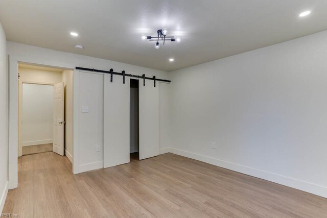 1413 Elm Ave, Portsmouth, VA 23704 - unfurnished bedroom with light wood-style floors, a barn door, baseboards, a closet, and recessed lighting