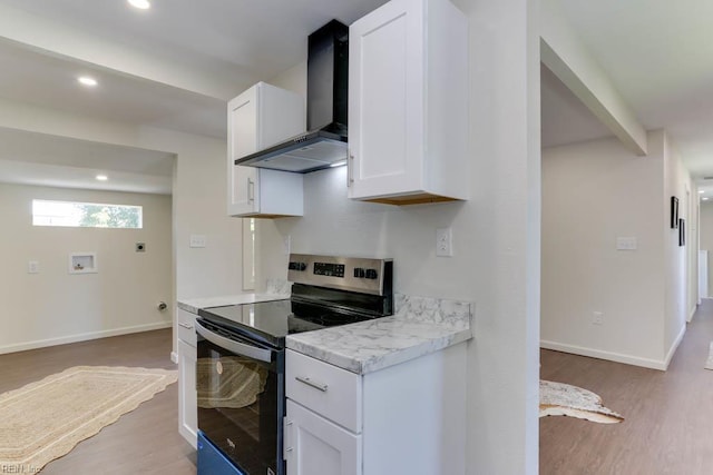 1413 Elm Ave, Portsmouth, VA 23704 - kitchen with stainless steel range with electric stovetop, wall chimney exhaust hood, light countertops, light wood-type flooring, and white cabinetry