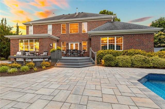 1704 Lower Church Ct, Virginia Beach, VA 23455 - back of property at dusk with outdoor dining area, brick siding, a deck, an outdoor pool, and a patio area