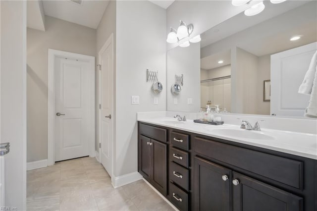 full bath featuring baseboards, double vanity, tiled shower, tile patterned flooring, and recessed lighting
