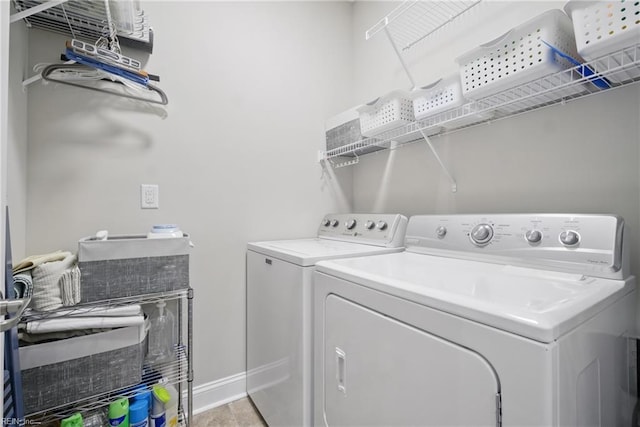 clothes washing area with washing machine and clothes dryer and baseboards