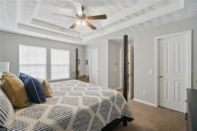 bedroom with a raised ceiling, light carpet, baseboards, and ceiling fan