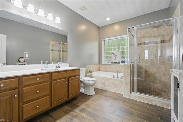 full bathroom featuring a bath, a stall shower, vanity, toilet, and wood finished floors