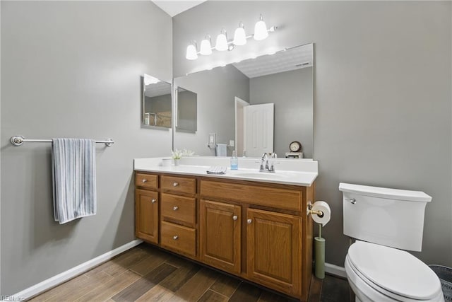 bathroom with wood finished floors, toilet, baseboards, and vanity
