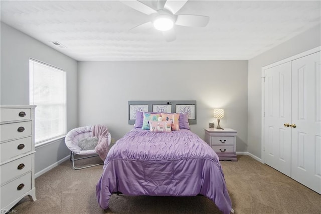 bedroom with light colored carpet, baseboards, a ceiling fan, and a closet