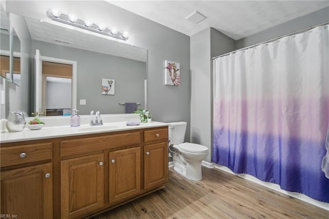 bathroom featuring wood finished floors, vanity, toilet, and curtained shower