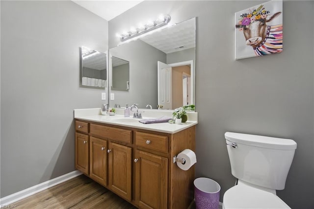 bathroom featuring toilet, wood finished floors, and vanity