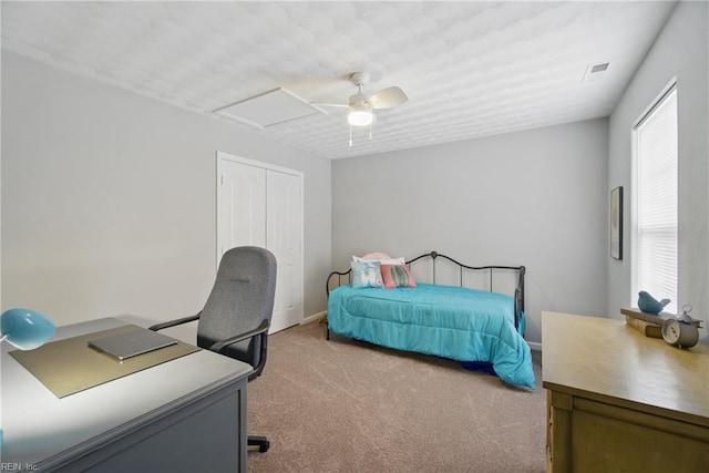 bedroom with light carpet, ceiling fan, a closet, a desk, and baseboards