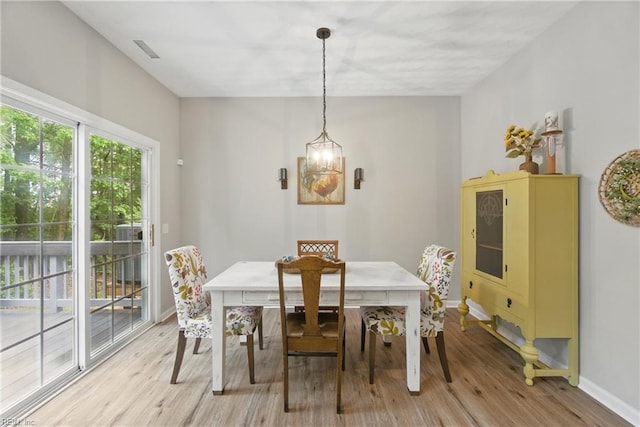 dining area featuring baseboards, light wood-style flooring, and a chandelier