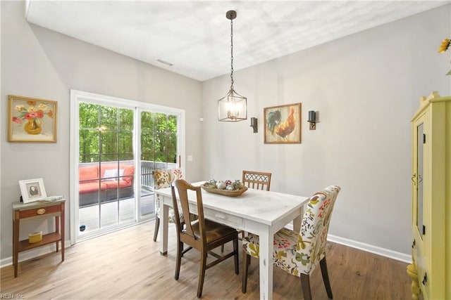 dining area featuring light wood-style floors, baseboards, and a chandelier