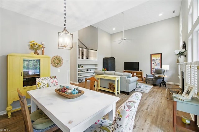 dining area with a towering ceiling, light wood-style floors, recessed lighting, baseboards, and ceiling fan