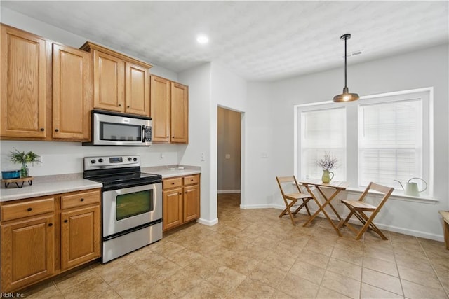 kitchen with appliances with stainless steel finishes, light countertops, hanging light fixtures, baseboards, and recessed lighting