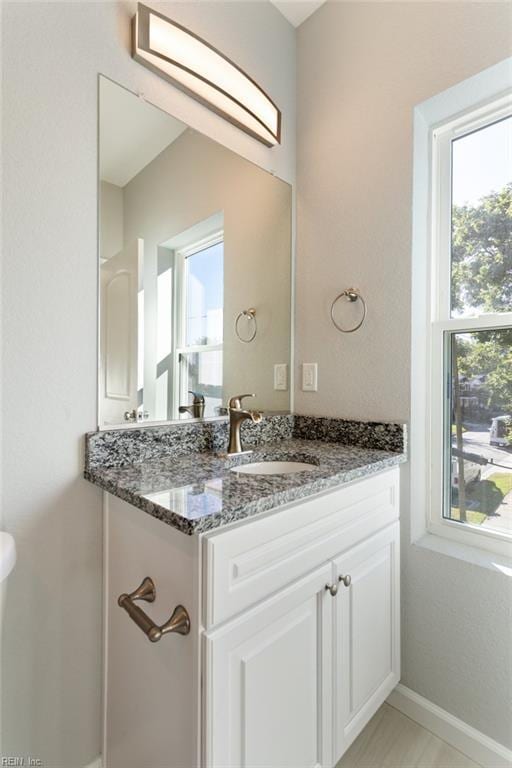 half bathroom with vanity and baseboards
