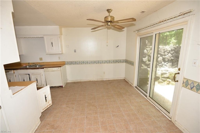 kitchen featuring white dishwasher, a sink, ceiling fan, white cabinets, and light flooring