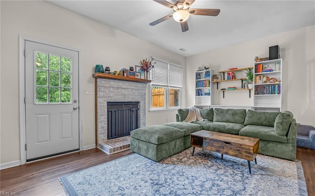 living area featuring wood finished floors, ceiling fan, a fireplace, and baseboards