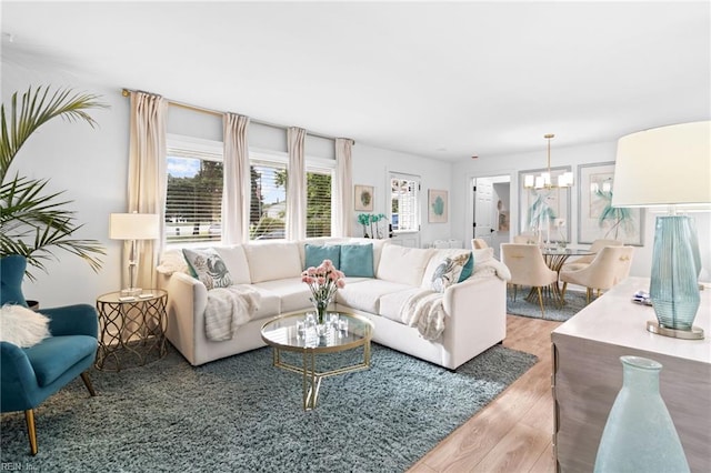 living room featuring healthy amount of natural light, wood finished floors, and a chandelier