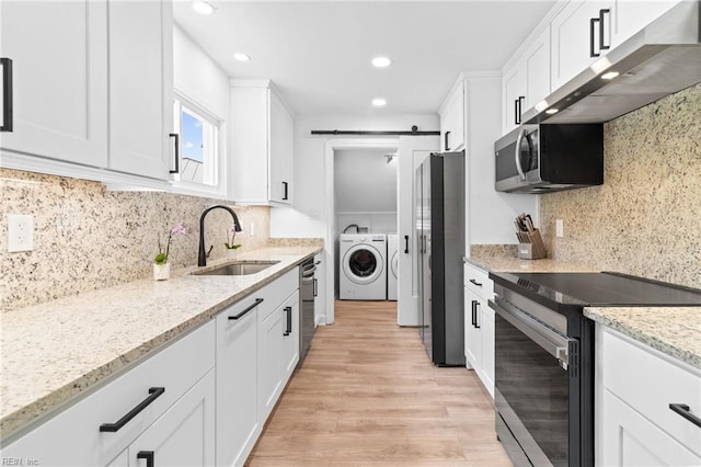kitchen featuring stainless steel appliances, separate washer and dryer, a sink, exhaust hood, and white cabinetry