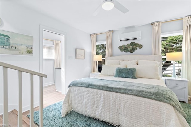 bedroom with an AC wall unit, multiple windows, light wood-style floors, and ceiling fan