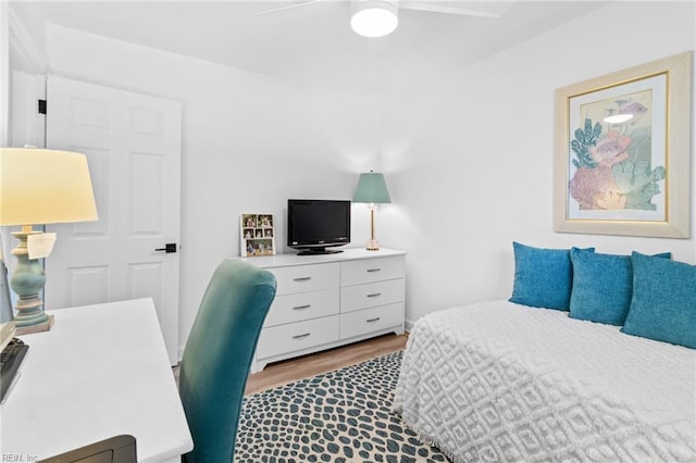 bedroom with wood finished floors, a ceiling fan, and an office area