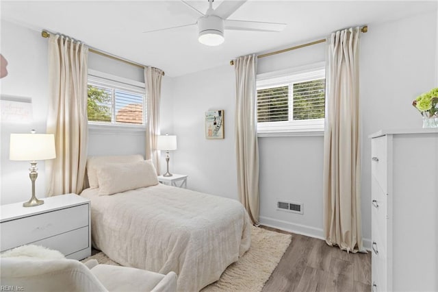bedroom featuring multiple windows, wood finished floors, a ceiling fan, and baseboards