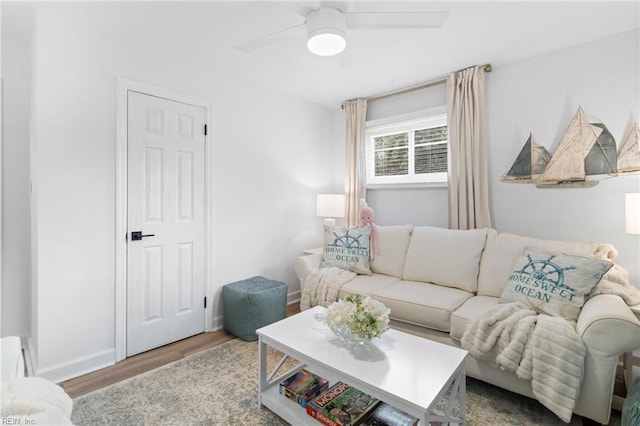 living area with wood finished floors, a ceiling fan, and baseboards