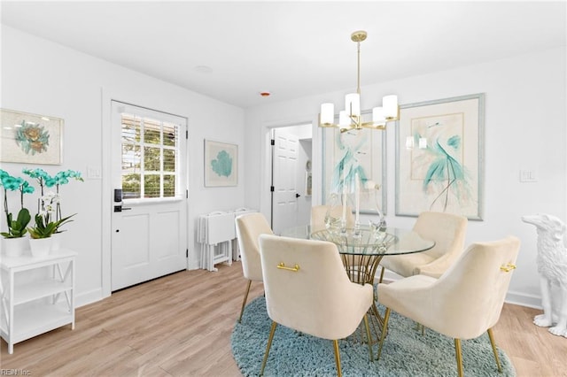 dining area with a chandelier, light wood finished floors, and baseboards