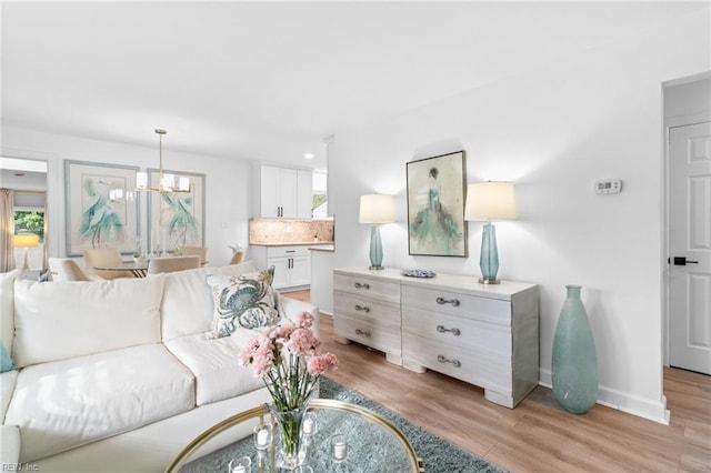 living area featuring light wood-type flooring, baseboards, a chandelier, and recessed lighting